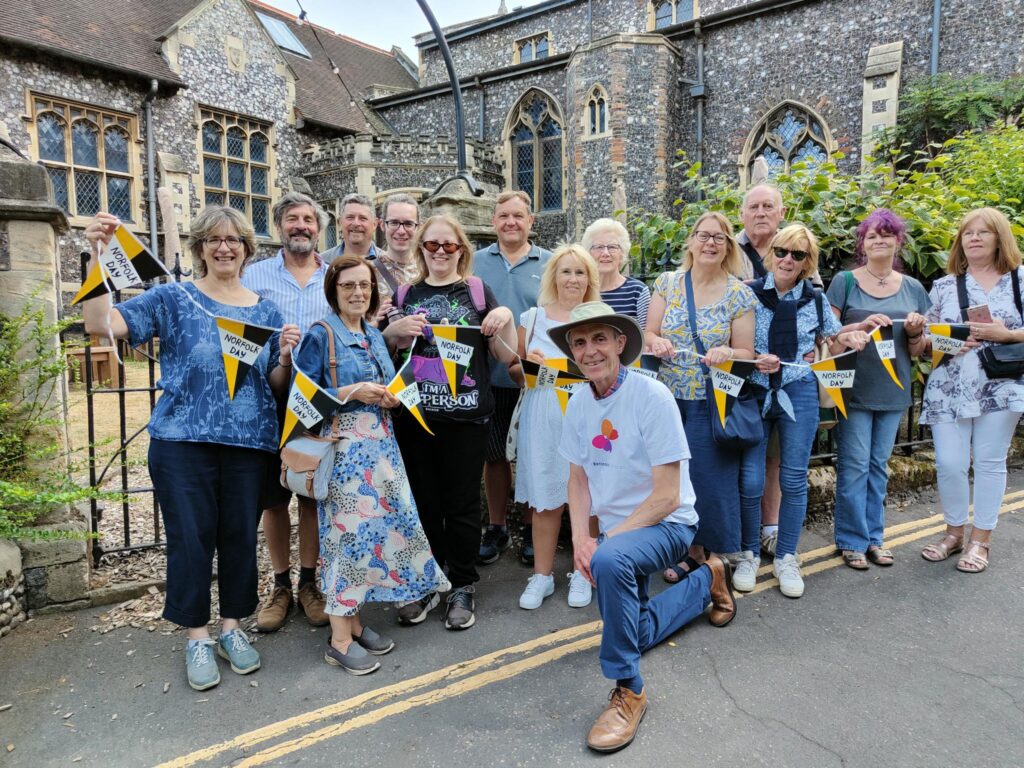 A group of people posing for a photo outside a historic church in Norwich